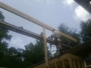 Carpenter setting a ridge beam over a new addition frame — Ice Dam Removal by Roofing Brothers in Flom