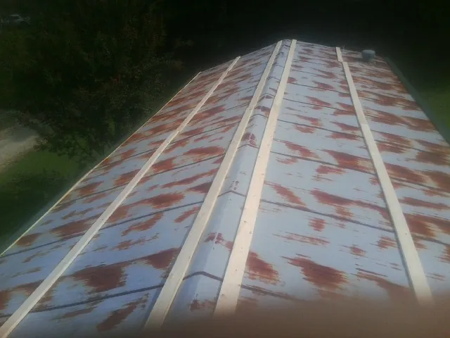 Rusted metal roof panels with new wood purlins before replacement — Storm Damage Roof Repair in Flom by Roofing Brothers
