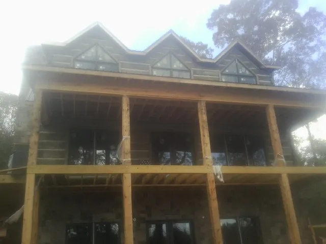 Dormers and porch framing on a large log home under construction — Roof Coating work by our crew in Flom