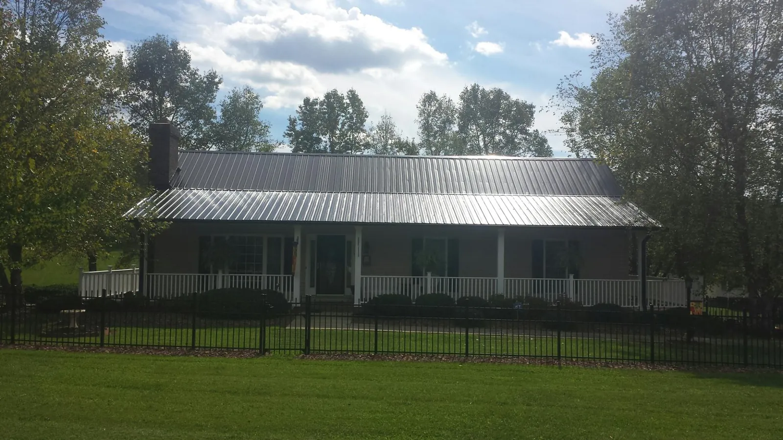 Gray metal roof on a brick ranch with a full width front porch — Gutter Guard Installation work by our crew in Flom