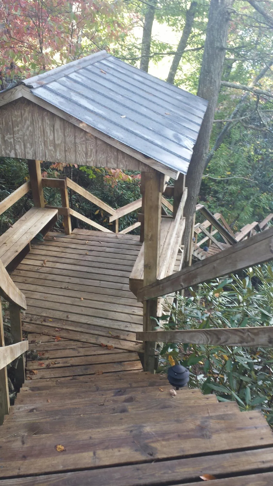 Metal roofed shelter over wooden steps on a wooded walkway — Skylight Repair & Installation work by our crew in Flom