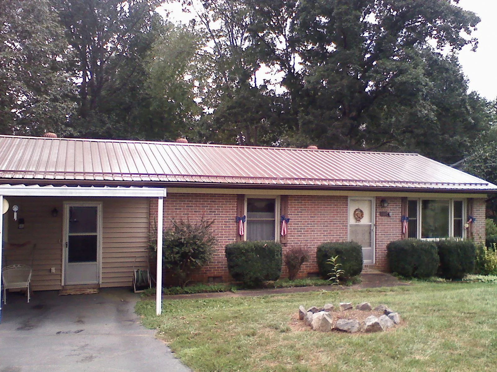 Bronze metal roof and carport on a brick ranch home — Roof Repair work by our crew in Flom
